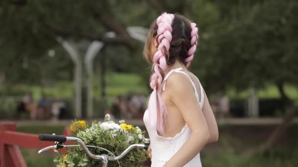 Mujer en vestido blanco mirando a la cámara mientras monta en el parque — Vídeos de Stock