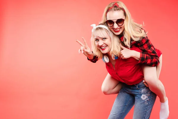 Hermanas que se divierten dando piggyback.Stock estudio retrato de dos alegres y positivas novias de moda o hermanas que se divierten . — Foto de Stock
