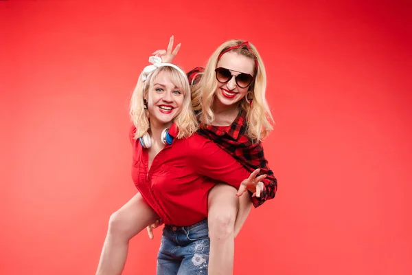 Sorelle divertirsi dando piggyback.Stock studio ritratto di due allegre e positive ragazze alla moda o sorelle divertirsi . — Foto Stock