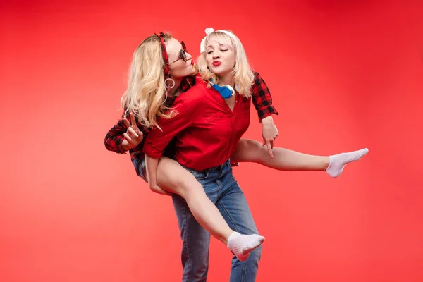 Sorelle divertirsi dando piggyback.Stock studio ritratto di due allegre e positive ragazze alla moda o sorelle divertirsi . — Foto Stock