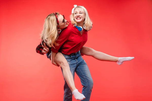 Filles amicales et à la mode étreignant sur fond rouge . — Photo