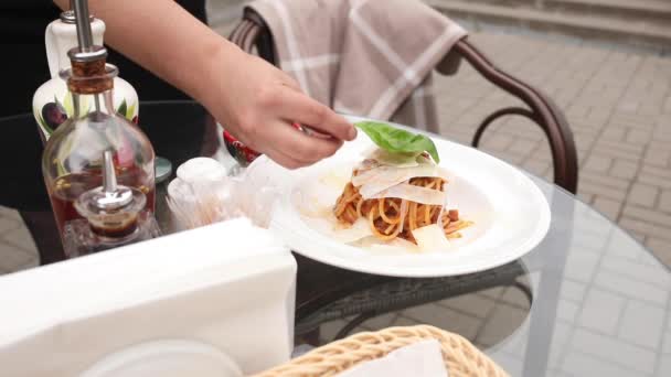 Close-up vrouwelijke hand serveren smakelijke pasta Bolognese met kaas blad groen en groente — Stockvideo