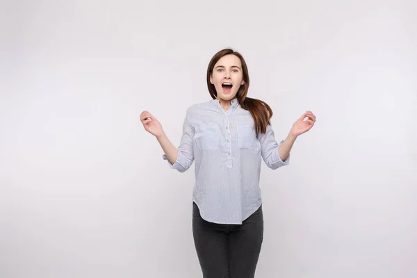 Amazed woman jumping with open mouth.Studio portrait of a young girl with brunette hair wearing casual clothes jumping because of surprise — Stock Photo, Image