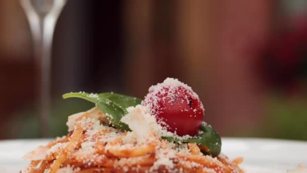 Close-up sprinkle grated tasty cheese parmesan to fresh appetizing pasta dish on plate at restaurant — Stock Video