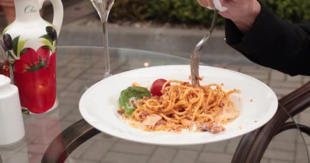 Vrouw eten pasta carbonara. Ze zet pasta op haar vork zittend op glazen tafel. — Stockvideo