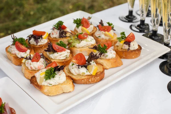 Delicious canape with sausage and tomato.Canapes on white ceramic plates at wedding reception. — Stock Photo, Image