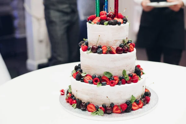 Háromrétegű esküvői torta friss bogyókkal.Eperrel, áfonyával, cseresznyével és szederrel díszítve. — Stock Fotó