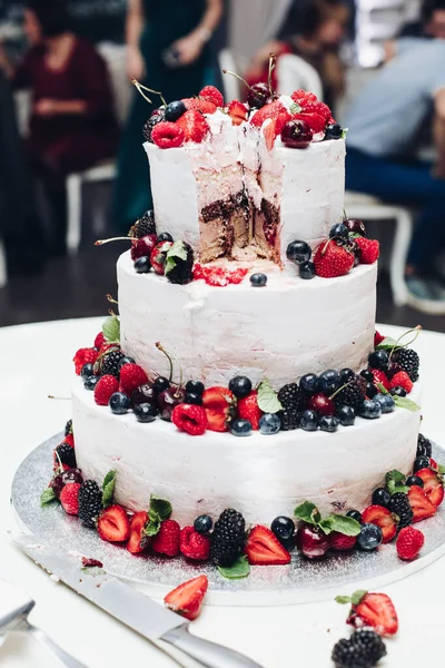 Nagy csodálatos esküvői ízletes torta fehér tejszínhabbal borított friss lédús bogyók és gyümölcsök — Stock Fotó