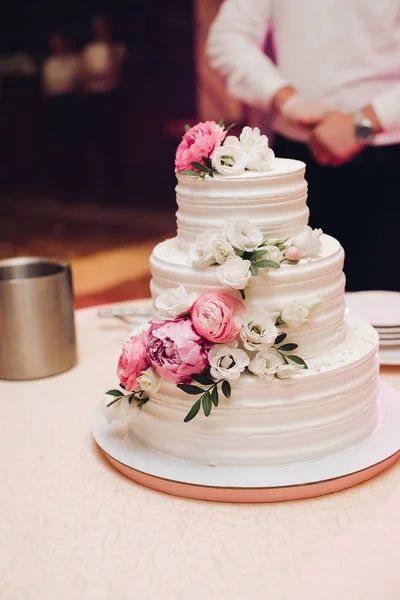 Étvágygerjesztő friss sütemény borított fehér krém cukormáz és díszíteni édes virág szolgálja fel az asztalon — Stock Fotó