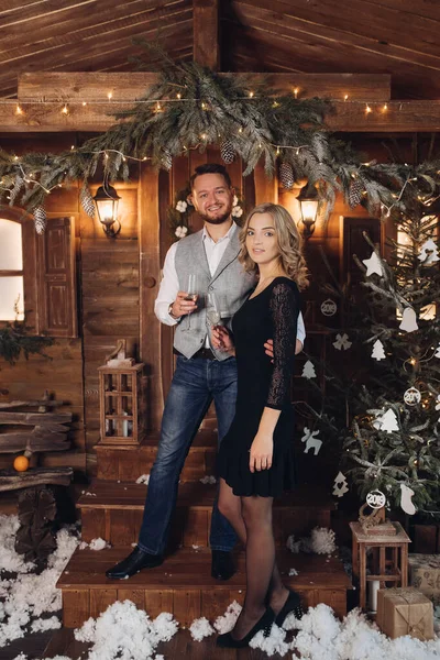 Belo casal com champanhe sob a grinalda de Natal . — Fotografia de Stock