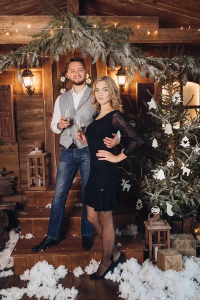 Belo casal com champanhe sob a grinalda de Natal . — Fotografia de Stock