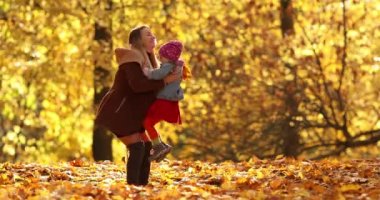 Siyah ceketli güzel kız mutlu annesiyle sonbahar parkında gülümsüyor ve seviniyor.