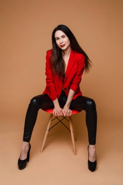 Güzel genç bir kadın sandalyede farklı pozlar veriyor, sarı arka planda izole edilmiş bir resim.