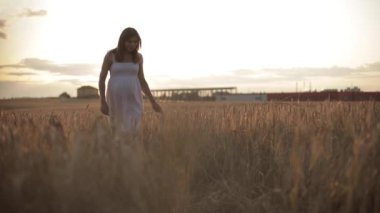 Pretty pregnant woman is walking during sunset