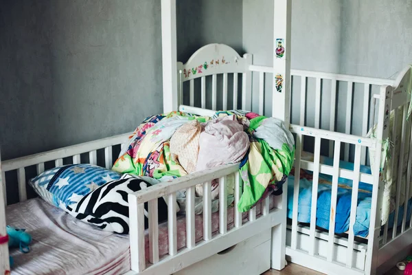 Fragment van een foto van een kinderkamer met verstrooide dingen, kussens en dekens op de bedden — Stockfoto