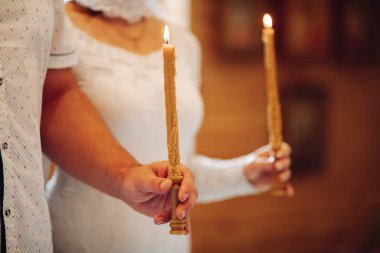 Vaftiz anne ve baba kilisede mum tutarlar.