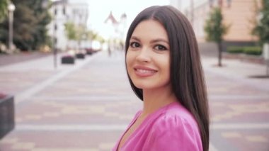 Güzel, mutlu genç bir kadın kameradan kaçar ve dışarıda güler.