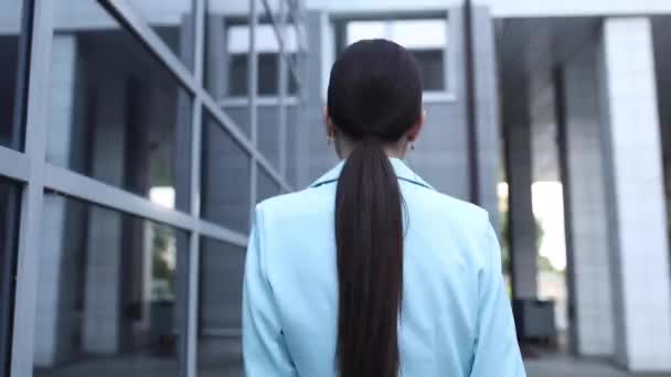 Une jeune femme avec un beau visage et une silhouette élancée allant au bureau et se retournant — Video