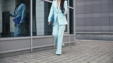 İş kadını bir klasör ve kağıt bardak taşıyor.