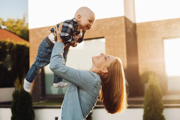 Glad ung kvinna leker med sitt lilla barn utomhus — Stockfoto