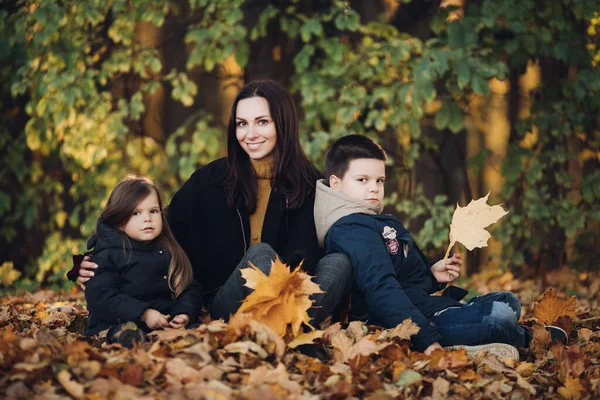白人の家族は2人の子供と一緒に秋の公園を散歩します — ストック写真