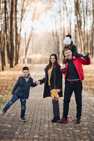 Caucasian family goes for a walk in the autumn park with two children — Stock Photo, Image
