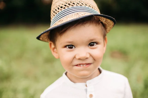 戴着夏帽的可爱的小男孩。在模糊的公园背景下，一个戴着夏帽的可爱学龄前小男孩在镜头前开心地微笑着。. — 图库照片