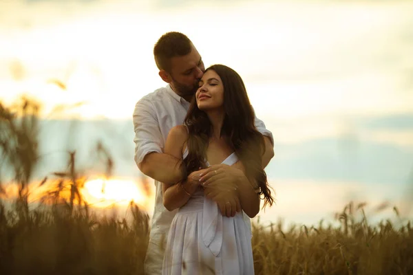 Mujer bastante caucásica con el pelo largo y ondulado oscuro en abrazos de vestido blanco con hermoso hombre en camiseta blanca y pantalones cortos —  Fotos de Stock