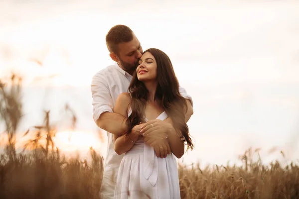 Mujer bastante caucásica con el pelo largo y ondulado oscuro en abrazos de vestido blanco con hermoso hombre en camiseta blanca y pantalones cortos —  Fotos de Stock