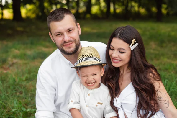 Foto van vrolijke jonge blanke vrouw en man houdt hun kind op handen, glimlacht en verheugt — Stockfoto