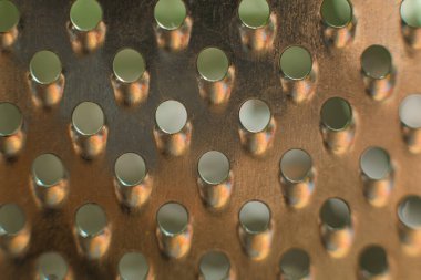 Üzerinde yuvarlak delikler olan sıradan metal mutfak rendesi.