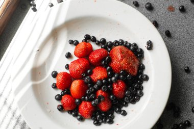 Siyah frenk üzümü ve tabakta çilek.