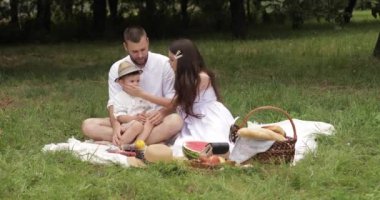 Neşeli beyaz anne, baba ve çocukları birlikte eğleniyor ve bahçede gülümsüyor.