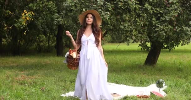 Joven hermosa mujer camina por el jardín con una cesta en sus manos y sonríe — Vídeos de Stock