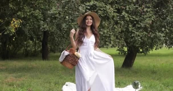 若い美しい女性は彼女の手にバスケットと庭を歩くと笑顔 — ストック動画