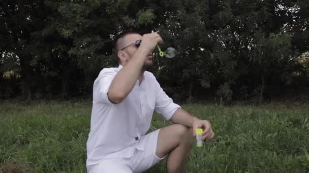 Joven padre sopla burbujas para su hijo feliz en el parque — Vídeo de stock