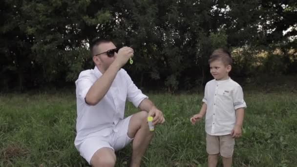 Vater und Sohn machen Seifenblasen. — Stockvideo