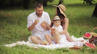 Ebeveynler ve oğulları piknikte fırın yiyorlar..