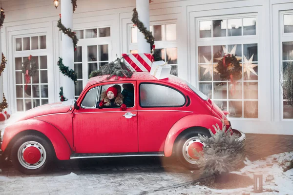 빨간 모자를 쓰고 차에 앉아서 신나게 놀고 있는 귀여운 겨울 소년 — 스톡 사진