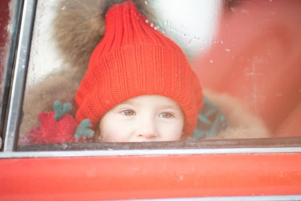 Χαμογελώντας χαριτωμένο κορίτσι του χειμώνα σε κόκκινο καπέλο κάθεται στο αυτοκίνητο διασκεδάζοντας — Φωτογραφία Αρχείου