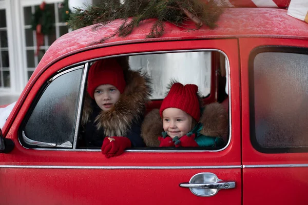 Χαμογελώντας χαριτωμένο αγόρι χειμώνα και τα παιδιά κορίτσι με κόκκινο καπέλο κάθεται στο αυτοκίνητο διασκεδάζοντας — Φωτογραφία Αρχείου