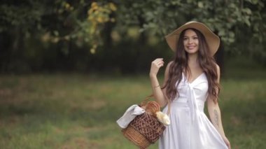 Hasır şapkalı güzel bayan parkta başıboş dolaşıyor.