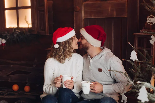 Imagem de dois belos amantes caucasianos com as mesmas camisolas, calças e meias sorri no estúdio de fotografia antes do Natal — Fotografia de Stock
