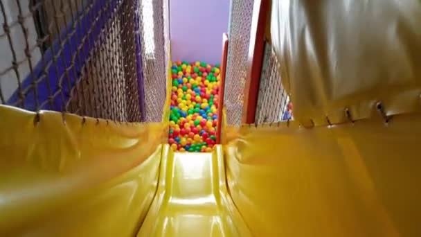 Sliding into colored plastic balls pool inside indoor activity room shot — Stock Video