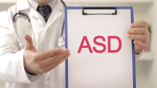 医生带着听诊器指向一个标有ASD标题的剪贴板作为诊断镜头 — 图库视频影像