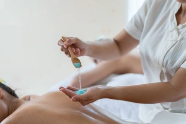 Masözün eli, tuzlu masaj yaptırırken Asyalı genç bir kadın kaplıcada dinlenirken arkaya tuz serpiyor. sağlıklı yaşam tarzı ve rahatlama kavramı