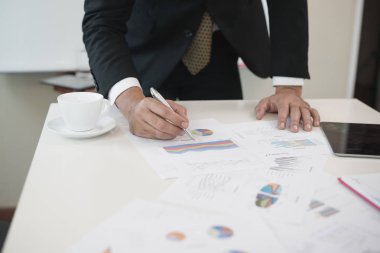 İş adamlarının eli ofis masasında iş evrakları yazıyor. Analiz ediyor. Beyin fırtınası konsepti.