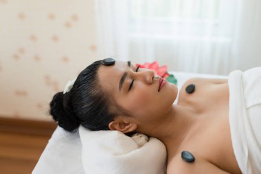 Genç ve güzel Asyalı kadın Spa Stone Masajı 'nda dinleniyor. Güzellik tedavisi ve rahatlatıcı konsept. Spa Sıcak Taşları
