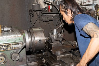 Torna tezgahında çalışan bir adam koruyucu giysi giymez. İş için güvenli değil.