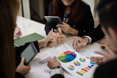 Bir grup iş adamı ve kadın iş pazarlama satış hedefinin grafiklerini görmek için bir araya geliyor. Takım çalışması iş toplantısı kavramı